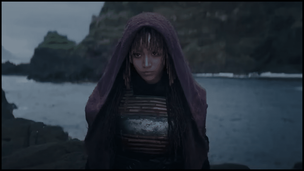 Woman in purple cloak by stormy seaside landscape.