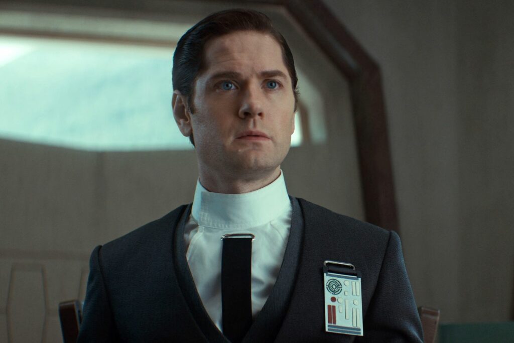 Syril Karn dressed in Imperial attire during a tense moment in Andor. His belief in law and order drives his actions, despite his naive trust in the Empire's ideals of justice.