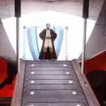 Obi-Wan Kenobi standing at the top of a spaceship ramp with Mustafar's fiery skies in the background.