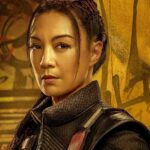 Ming-Na Wen smiling in her Fennec Shand costume behind the scenes on a Star Wars set.