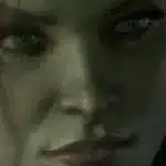 Close-up cinematic render of Poison Ivy’s face from Batman: Arkham Knight with glowing green eyes and detailed skin texture.