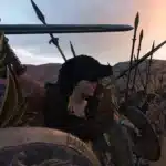 Female warrior leading a shield wall in Mount & Blade II: Bannerlord with spears raised at sunset.