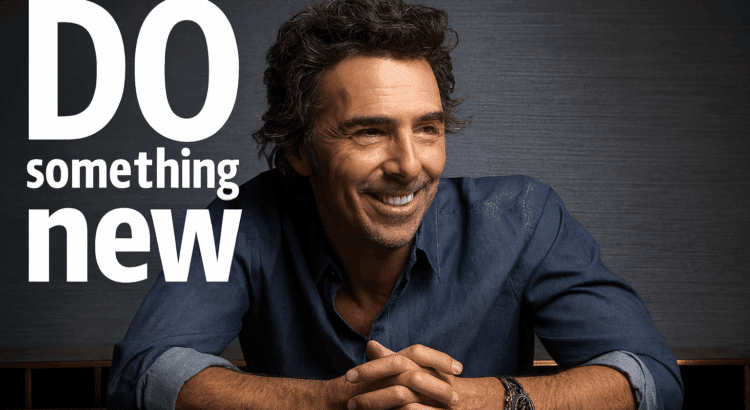 Portrait of director Shawn Levy smiling at a table, with the phrase “Do Something New” in bold white text beside him.