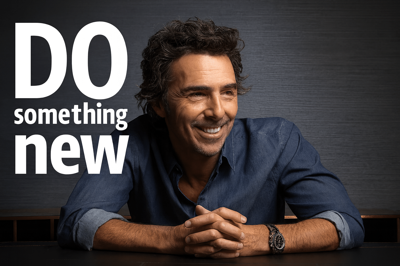 Portrait of director Shawn Levy smiling at a table, with the phrase “Do Something New” in bold white text beside him.