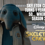 Promotional image featuring the blue alien character from Skeleton Crew standing outdoors, with bold white text reading “Skeleton Crew Turns 1 Year Old — So… Where’s Season 2?” along with the Disney+ and Star Wars Skeleton Crew logos.